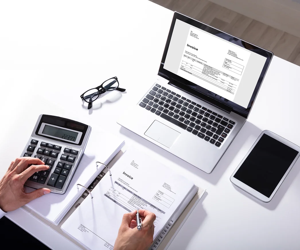 High Angle View Of Businessperson Calculating Invoice With Laptop On Desk